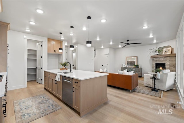 kitchen with ceiling fan, a kitchen island with sink, hanging light fixtures, stainless steel dishwasher, and sink