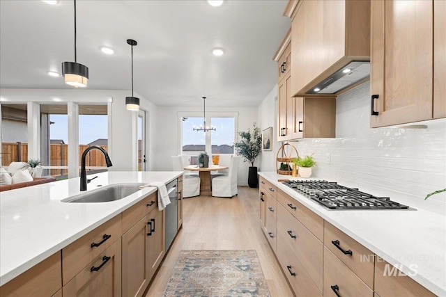 kitchen featuring appliances with stainless steel finishes, decorative light fixtures, tasteful backsplash, premium range hood, and sink