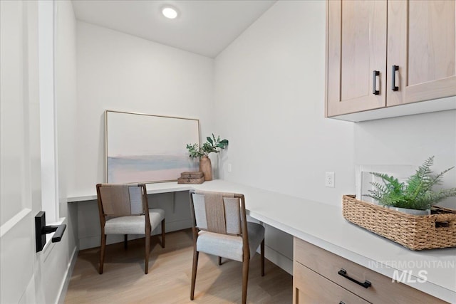 home office featuring light hardwood / wood-style floors and built in desk