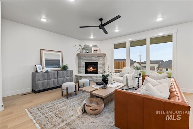 living room featuring ceiling fan, a fireplace, and light hardwood / wood-style floors