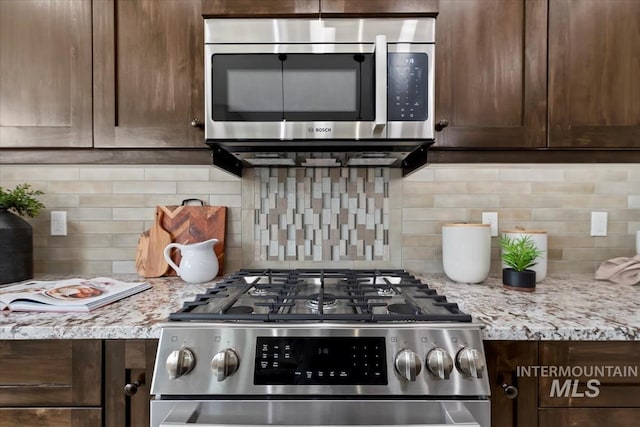 kitchen with decorative backsplash, dark brown cabinetry, light stone counters, and stainless steel appliances