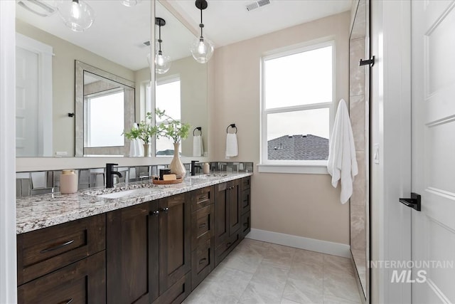 full bathroom with double vanity, baseboards, visible vents, and a sink