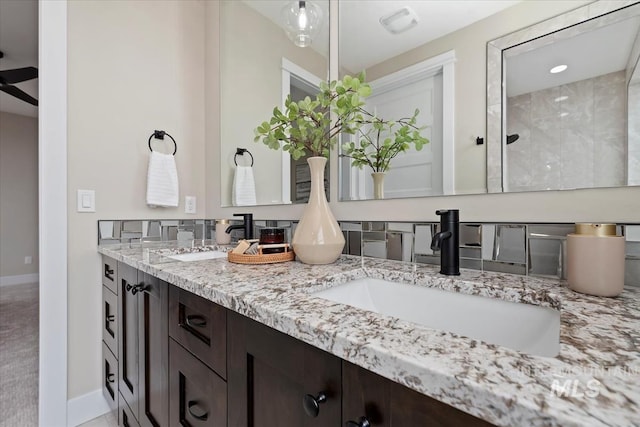 full bathroom featuring double vanity, baseboards, and a sink