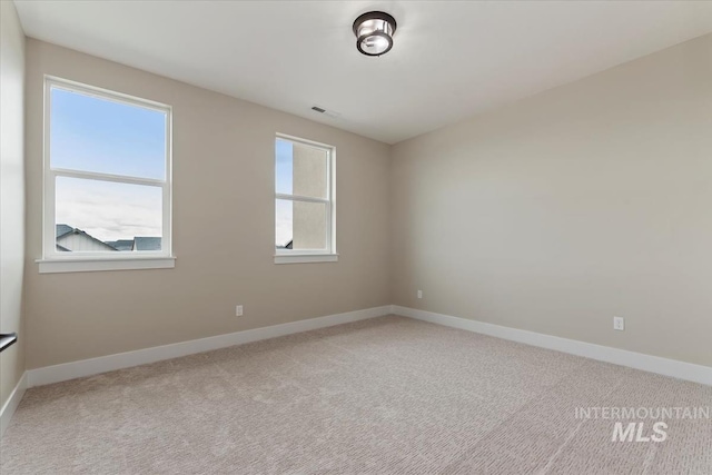 spare room featuring baseboards, light carpet, and visible vents