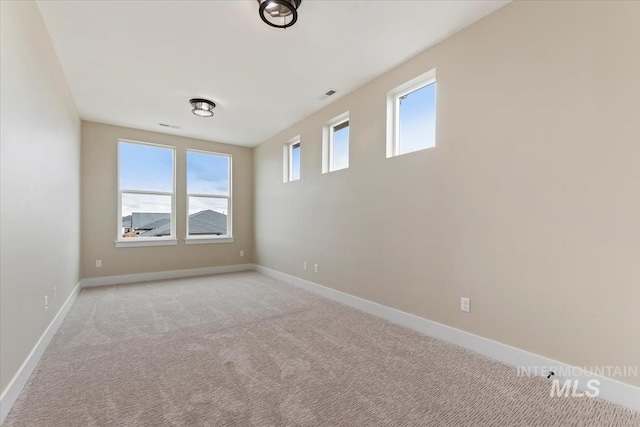 spare room with visible vents, a healthy amount of sunlight, baseboards, and light carpet