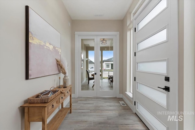 entryway featuring french doors, visible vents, light wood finished floors, and baseboards