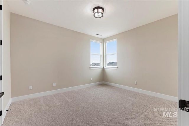 spare room featuring visible vents, light colored carpet, and baseboards