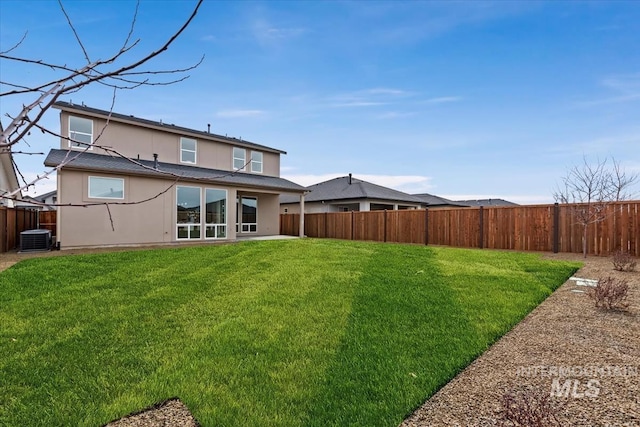 rear view of property featuring a yard, stucco siding, and a fenced backyard