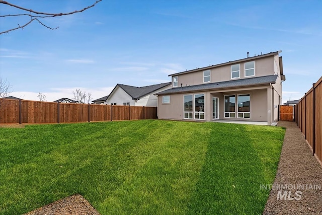 rear view of house featuring a fenced backyard, a lawn, and stucco siding