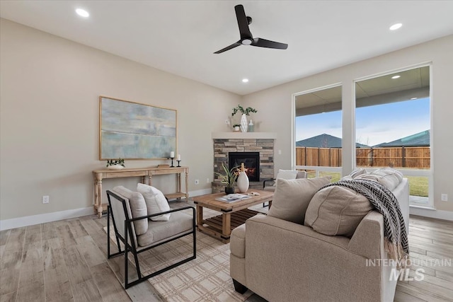 living area featuring light wood finished floors, baseboards, ceiling fan, recessed lighting, and a fireplace