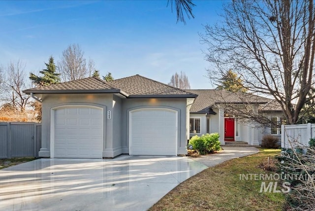 view of front facade featuring an attached garage, fence, driveway, and stucco siding