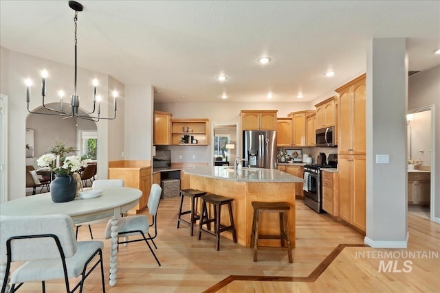 kitchen featuring open shelves, a chandelier, a kitchen breakfast bar, stainless steel appliances, and a kitchen island with sink