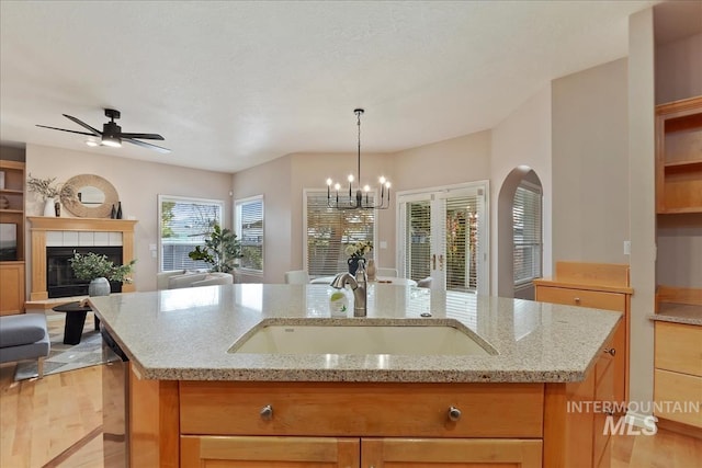 kitchen with open floor plan, a fireplace, light wood-style floors, arched walkways, and a sink