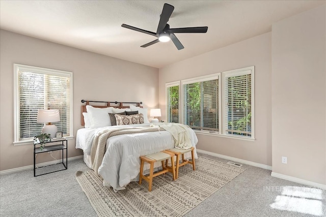 carpeted bedroom featuring multiple windows, baseboards, and visible vents