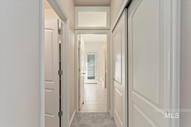 hall with light colored carpet and light tile patterned flooring