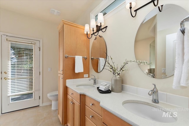 bathroom featuring a sink, toilet, double vanity, and tile patterned flooring