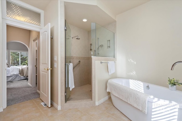 ensuite bathroom with a freestanding tub, tiled shower, and tile patterned flooring