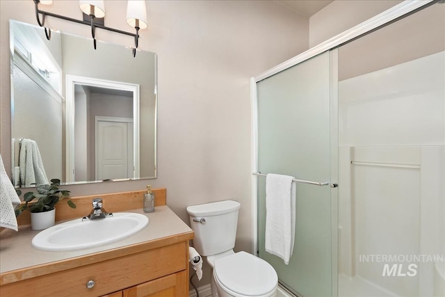 full bathroom with vanity, a shower stall, and toilet