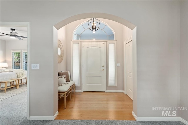 entryway with light wood-type flooring, baseboards, arched walkways, and ceiling fan