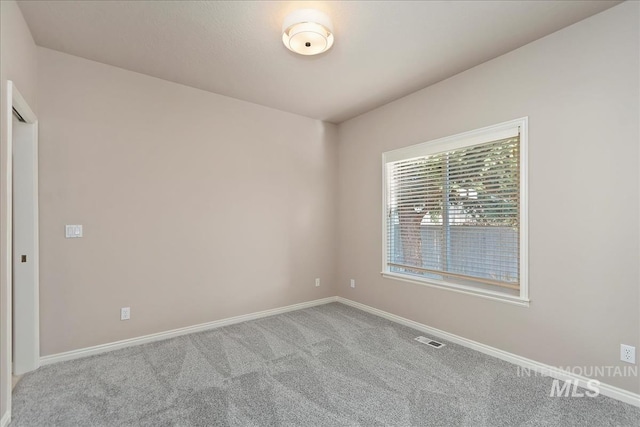 carpeted spare room featuring visible vents and baseboards