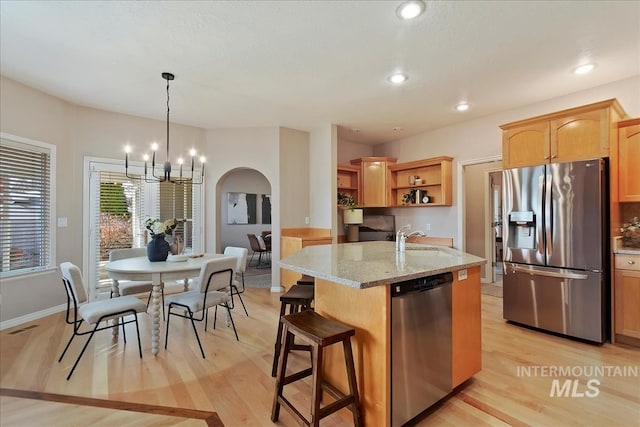 kitchen featuring visible vents, open shelves, appliances with stainless steel finishes, arched walkways, and a sink