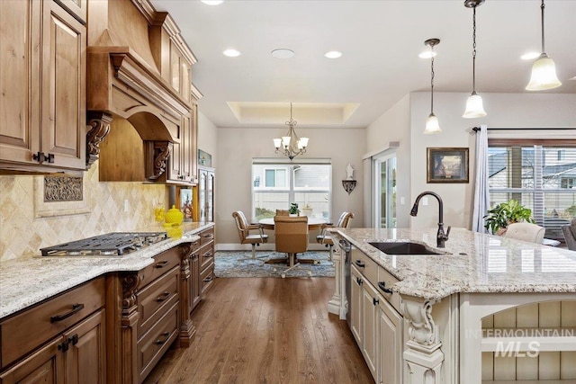 kitchen featuring tasteful backsplash, a kitchen island with sink, sink, and decorative light fixtures