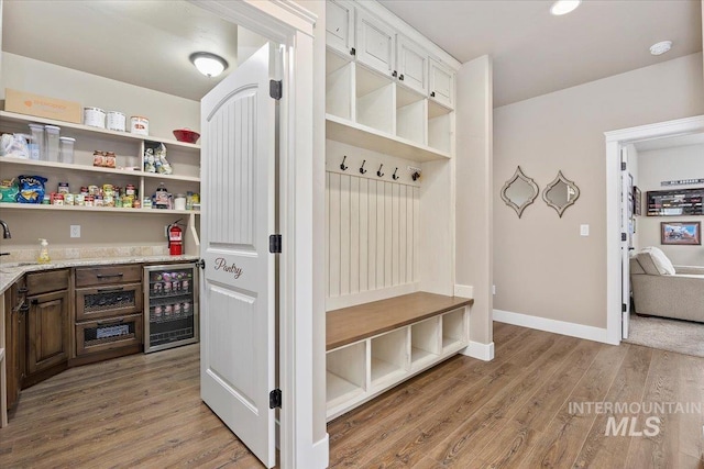 mudroom featuring light wood-type flooring, sink, and beverage cooler