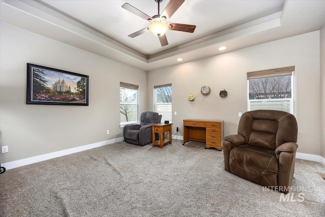 sitting room with a tray ceiling, ceiling fan, and carpet floors