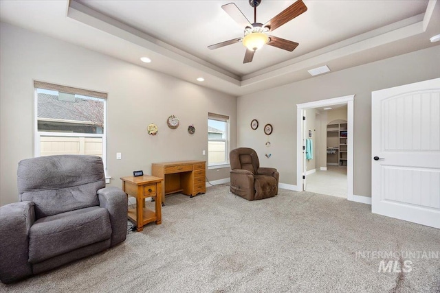 sitting room with a raised ceiling, ceiling fan, and light carpet