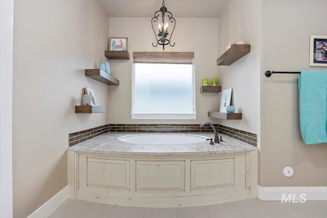 bathroom featuring tile patterned flooring, a chandelier, tasteful backsplash, and a bathtub