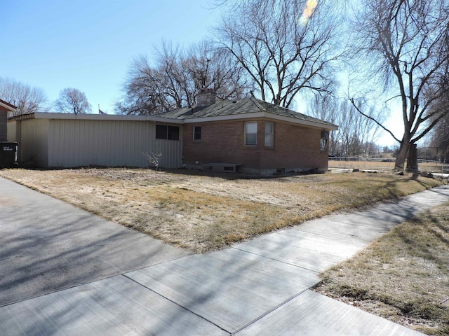 view of property exterior featuring brick siding and a chimney