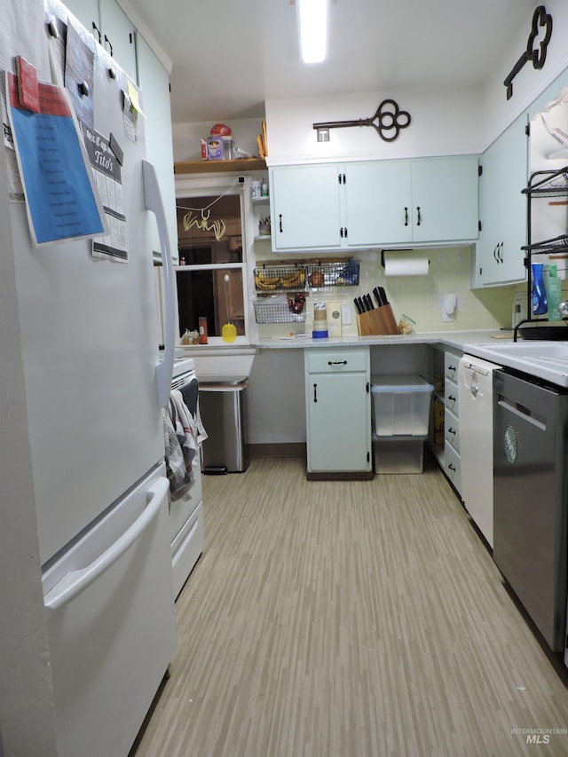 kitchen featuring light wood-type flooring, white appliances, light countertops, and a sink