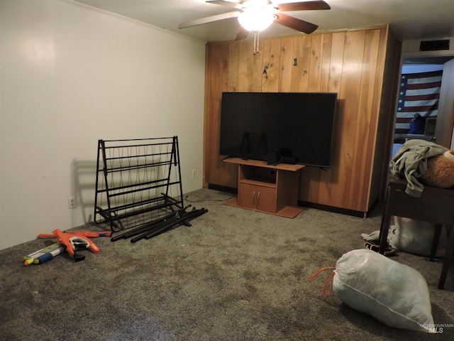 living area featuring visible vents, wood walls, carpet, and a ceiling fan