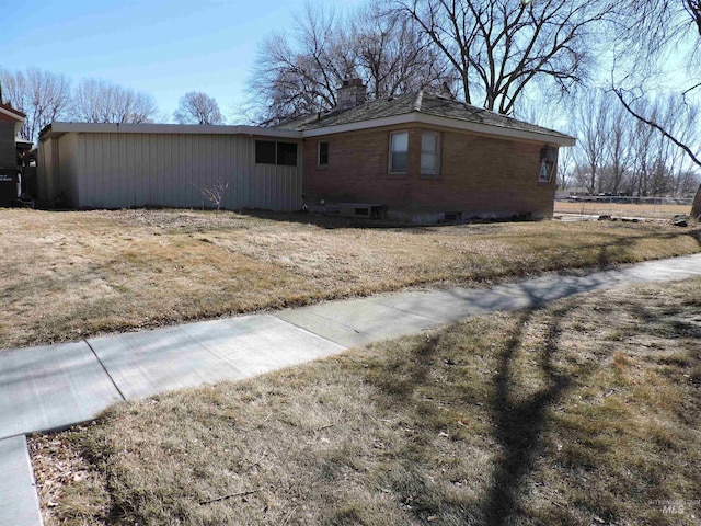 view of home's exterior featuring a yard, a chimney, and brick siding