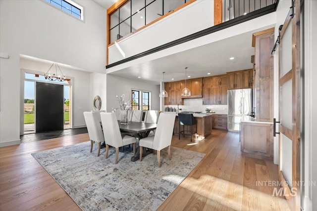 8860 Kemp Rd, Middleton, ID 83607 - dining area featuring a barn door, a high ceiling, light wood finished floors, a chandelier, and recessed lighting