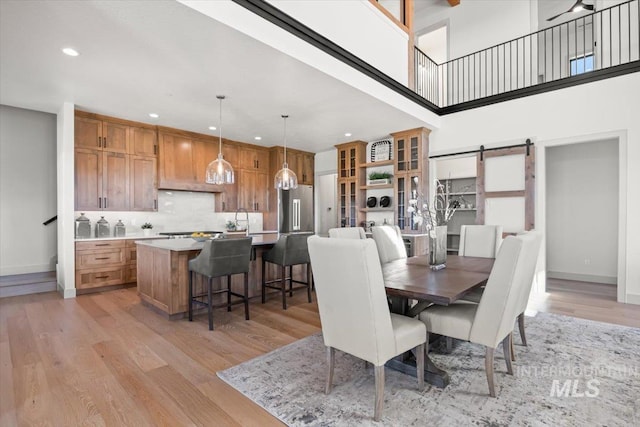 8860 Kemp Rd, Middleton, ID 83607 - dining room with light wood finished floors, a barn door, recessed lighting, baseboards, and a towering ceiling
