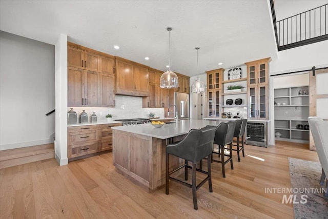 8860 Kemp Rd, Middleton, ID 83607 - kitchen featuring stainless steel appliances, light wood-style floors, light countertops, a breakfast bar, and brown cabinets