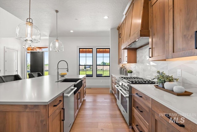 8860 Kemp Rd, Middleton, ID 83607 - kitchen featuring stainless steel appliances, a sink, brown cabinetry, light wood-type flooring, and a textured ceiling