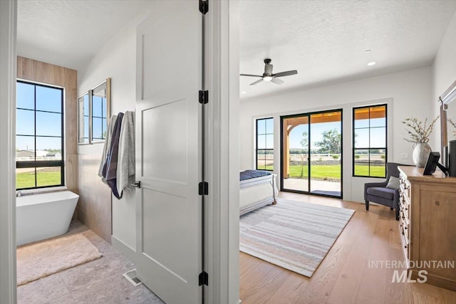 8860 Kemp Rd, Middleton, ID 83607 - bathroom featuring a freestanding bath, a textured ceiling, ceiling fan, recessed lighting, and wood finished floors