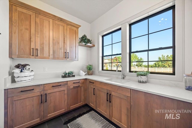 8860 Kemp Rd, Middleton, ID 83607 - kitchen with a sink, dark tile patterned floors, light countertops, open shelves, and brown cabinets