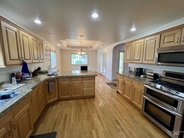 315 Shadetree Trl, Twin Falls, ID 83301 - kitchen featuring stainless steel appliances, a peninsula, a raised ceiling, a chandelier, and arched walkways