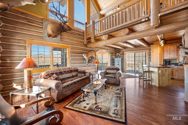 living room with beamed ceiling, log walls, a high ceiling, and dark hardwood / wood-style flooring