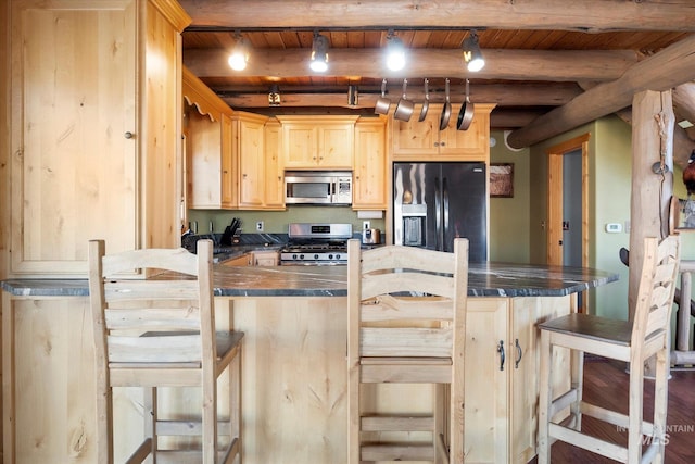 kitchen with light brown cabinetry, appliances with stainless steel finishes, and a breakfast bar