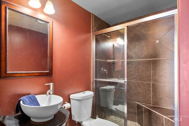 bathroom featuring an enclosed shower, toilet, and sink