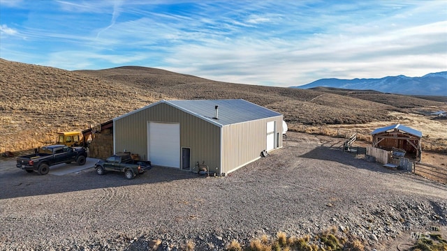 rear view of property with a mountain view, an outdoor structure, and a garage