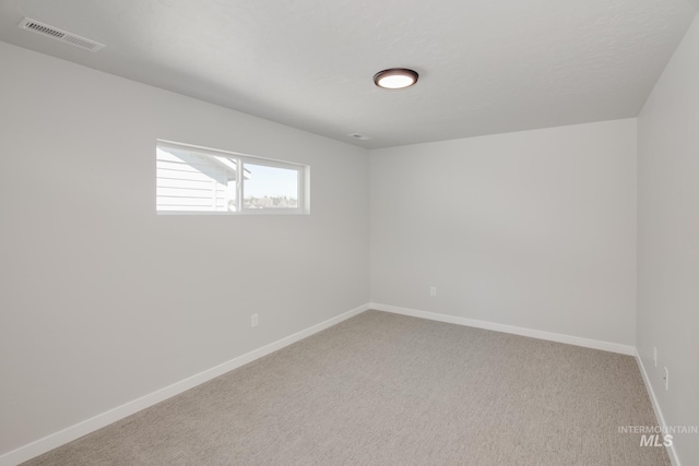 carpeted spare room featuring visible vents and baseboards