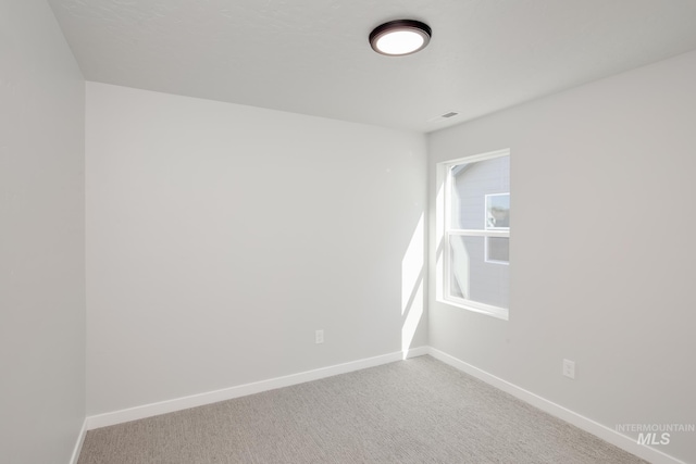empty room featuring baseboards and light carpet