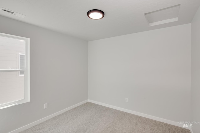 carpeted empty room featuring attic access, visible vents, and baseboards