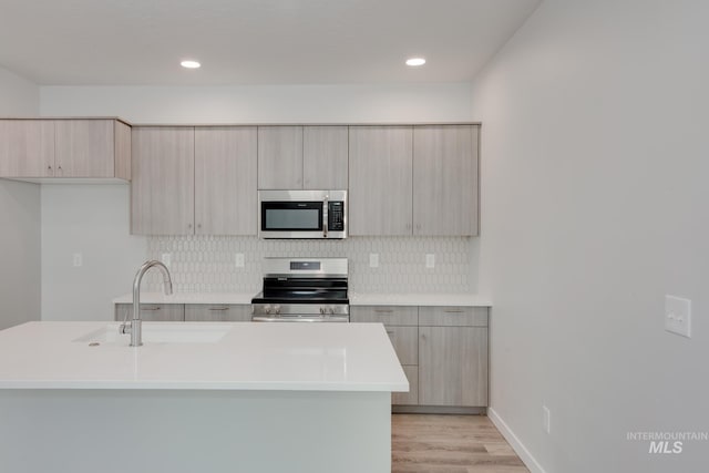 kitchen featuring light countertops, stainless steel appliances, modern cabinets, and a sink