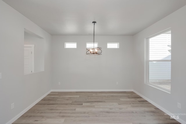 unfurnished dining area with light wood-style floors, baseboards, and a notable chandelier